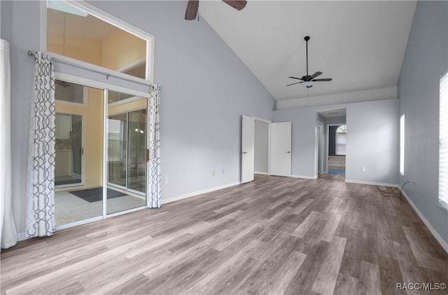 unfurnished living room with wood finished floors, ceiling fan, plenty of natural light, and high vaulted ceiling