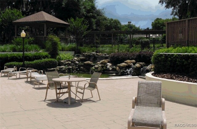 view of patio with fence, a gazebo, outdoor dining space, and a mountain view