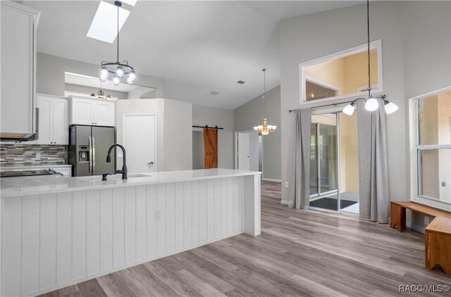 kitchen with a sink, a chandelier, a barn door, stainless steel fridge, and light countertops