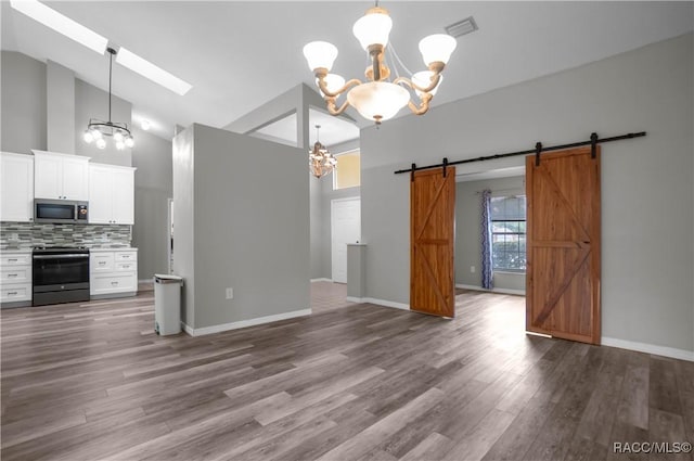 unfurnished dining area with a notable chandelier, wood finished floors, a barn door, and visible vents