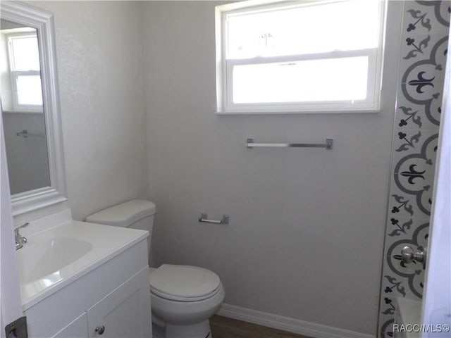 bathroom with vanity, toilet, and a healthy amount of sunlight