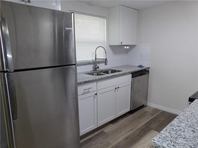 kitchen with white cabinetry, sink, light stone countertops, dark hardwood / wood-style flooring, and appliances with stainless steel finishes