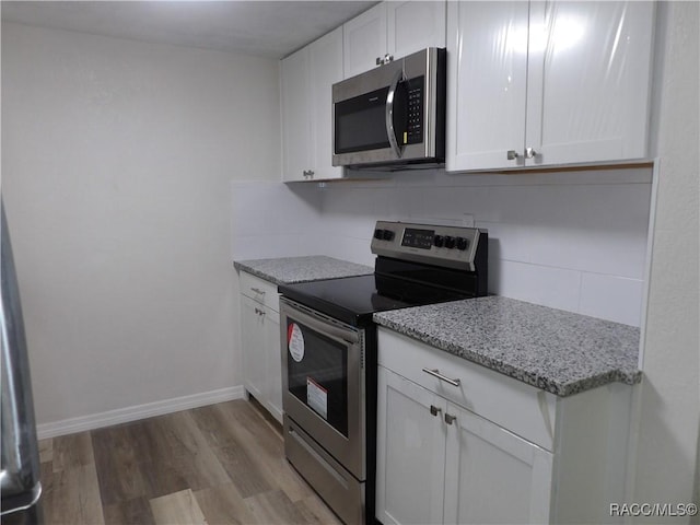 kitchen featuring backsplash, light stone counters, stainless steel appliances, light hardwood / wood-style flooring, and white cabinets