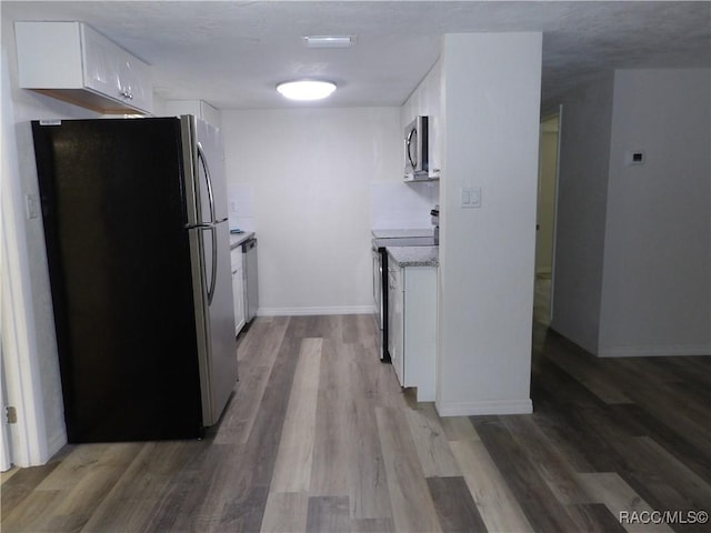 kitchen featuring stainless steel appliances, white cabinetry, and hardwood / wood-style flooring