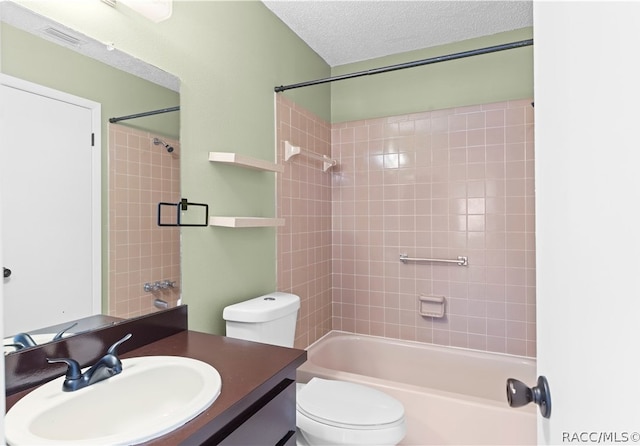 full bathroom with vanity, toilet, a textured ceiling, and tiled shower / bath