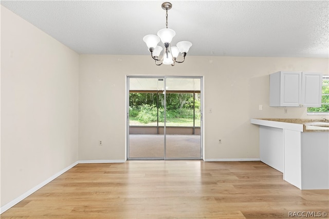 unfurnished dining area featuring a notable chandelier, light wood-type flooring, and a wealth of natural light