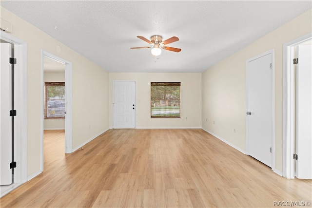 spare room featuring a textured ceiling, light wood-type flooring, and a wealth of natural light