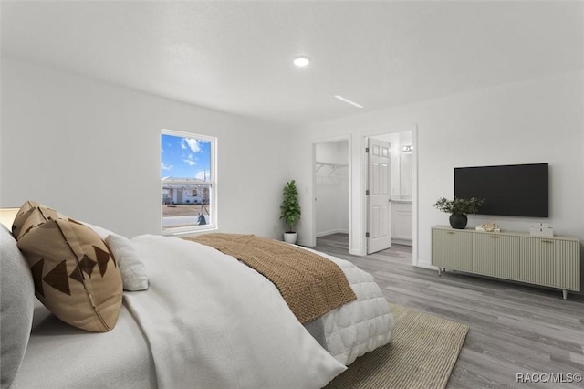 bedroom featuring a spacious closet, a closet, ensuite bathroom, and light hardwood / wood-style floors