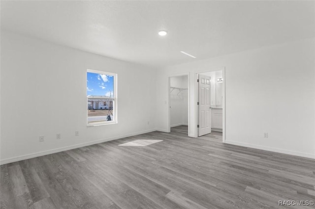 unfurnished bedroom featuring a spacious closet and hardwood / wood-style floors