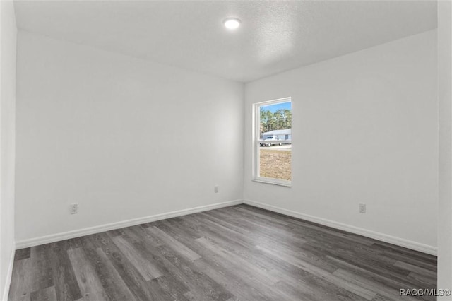 unfurnished room with a textured ceiling and dark hardwood / wood-style floors