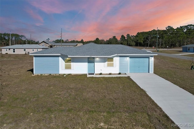 ranch-style house featuring a garage and a yard