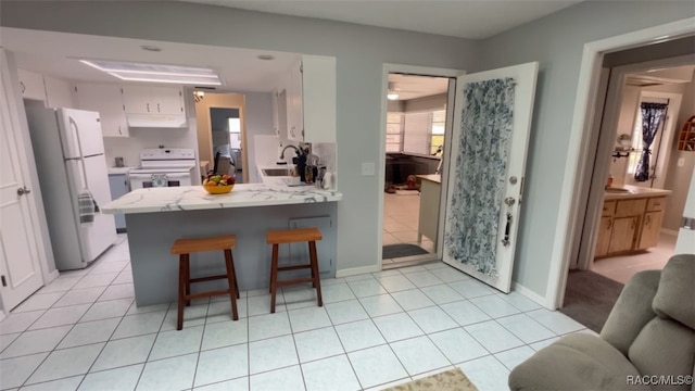 kitchen with white cabinets, sink, white appliances, and kitchen peninsula