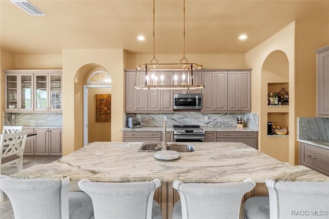 5061 W Oakhill St, Dunnellon, FL 34433 - kitchen with stainless steel appliances, an island with sink, backsplash, light stone countertops, and a kitchen bar