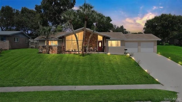 1316 Lake Ariana Blvd, Auburndale, FL 33823 - view of front of property with an attached garage, stone siding, driveway, a lawn, and stucco siding
