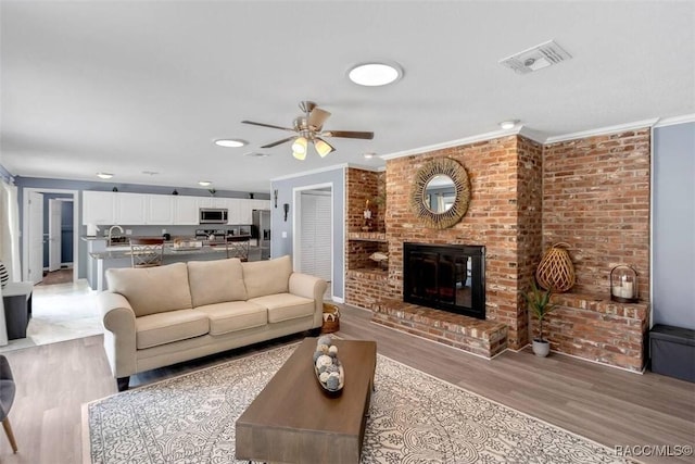 1316 Lake Ariana Blvd, Auburndale, FL 33823 - living area with light wood-style flooring, ornamental molding, a ceiling fan, and a brick fireplace