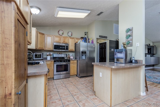 kitchen with a kitchen breakfast bar, light brown cabinetry, lofted ceiling, and appliances with stainless steel finishes