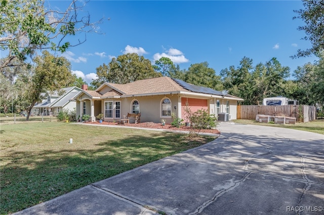 ranch-style home with central air condition unit, a front lawn, and solar panels