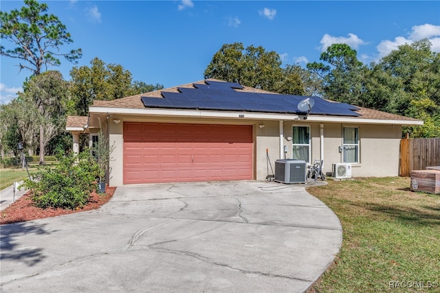 ranch-style home with solar panels, ac unit, central AC unit, a front yard, and a garage