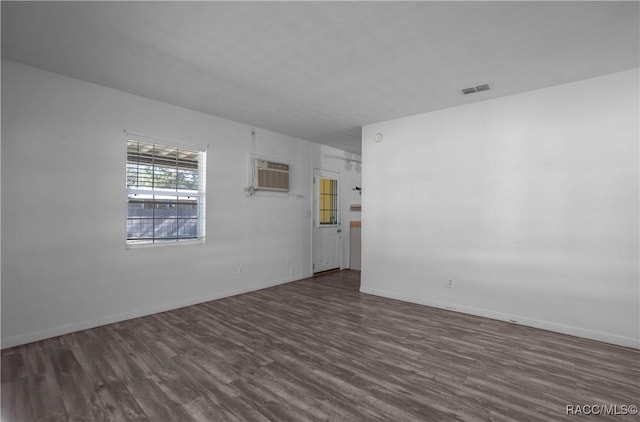 spare room with a wall mounted AC and dark hardwood / wood-style flooring