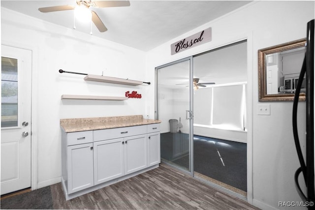 kitchen with dark wood-type flooring, ceiling fan, and black fridge