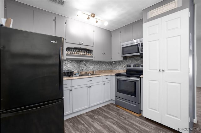 kitchen featuring dark wood-type flooring, sink, tasteful backsplash, gray cabinets, and stainless steel appliances