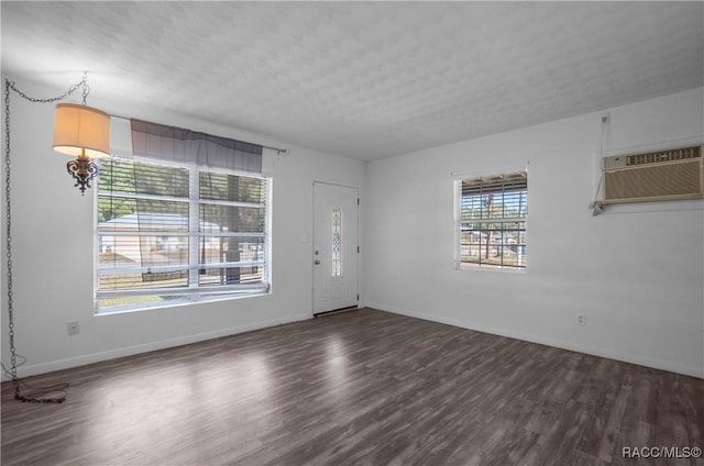 unfurnished room with dark wood-type flooring, a textured ceiling, and an AC wall unit