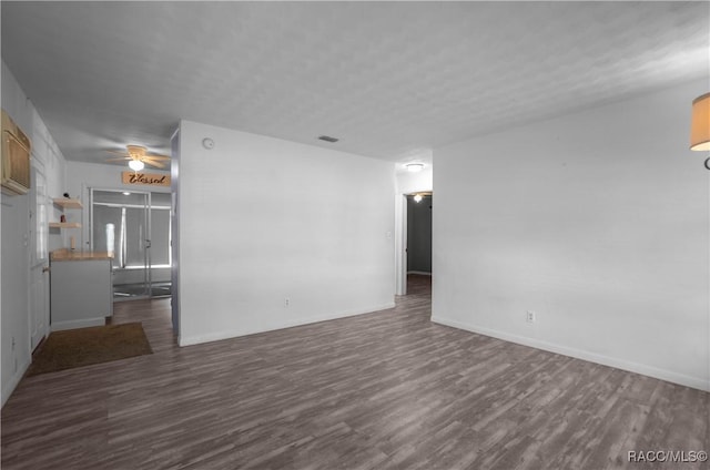 unfurnished living room with dark wood-type flooring, a textured ceiling, and ceiling fan