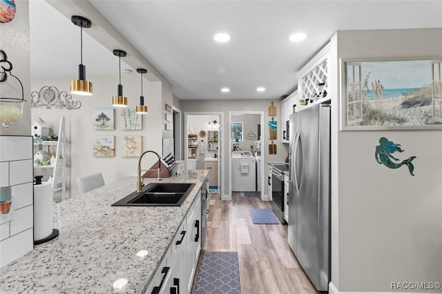 2 William Tell Ln, Beverly Hills, FL 34465 - kitchen featuring stainless steel appliances, washer / dryer, light wood-style floors, white cabinetry, and light stone counters
