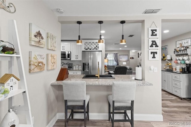 2 William Tell Ln, Beverly Hills, FL 34465 - kitchen featuring appliances with stainless steel finishes, a peninsula, a kitchen bar, pendant lighting, and light wood-type flooring