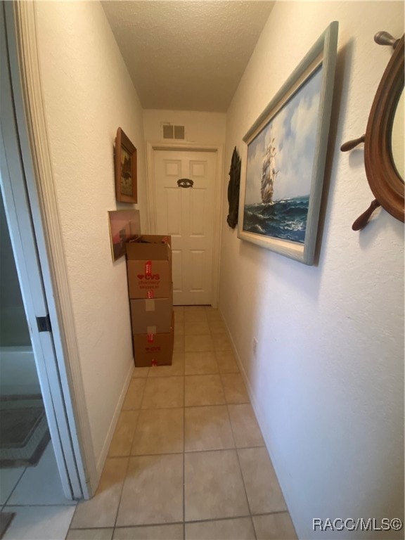 hallway featuring light tile patterned flooring and a textured ceiling