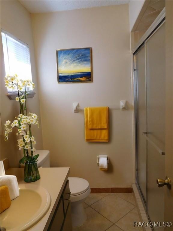 bathroom with an enclosed shower, vanity, tile patterned flooring, and toilet