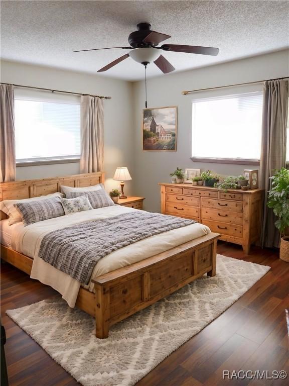 bedroom with ceiling fan, dark hardwood / wood-style flooring, and a textured ceiling