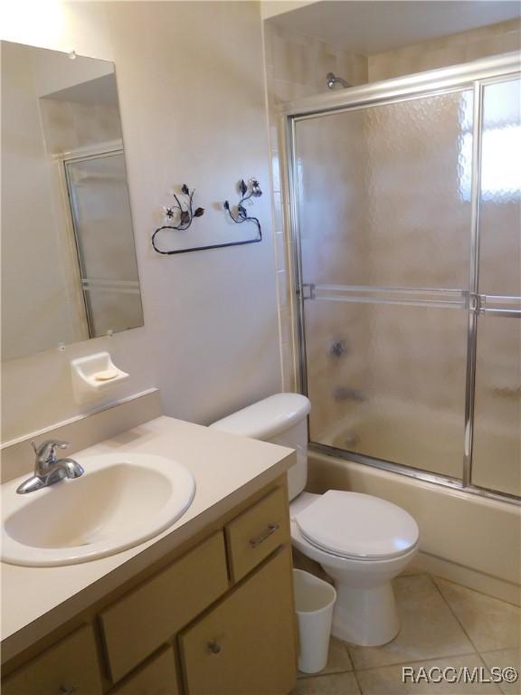 full bathroom with tile patterned flooring, vanity, toilet, and bath / shower combo with glass door