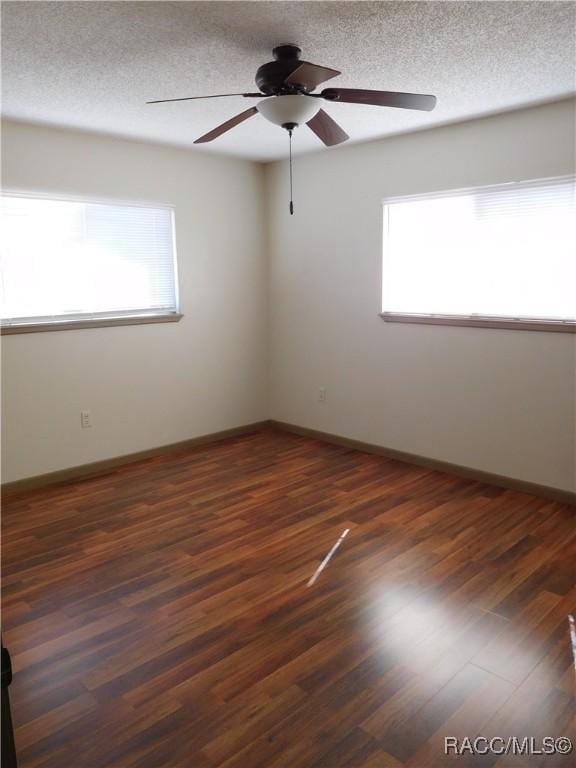 spare room featuring ceiling fan, dark hardwood / wood-style floors, and a textured ceiling