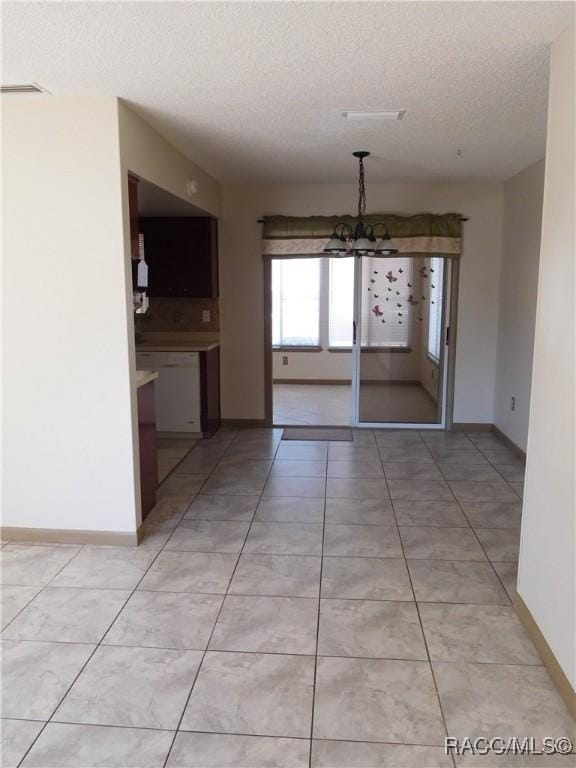 unfurnished dining area featuring light tile patterned floors, a textured ceiling, and a notable chandelier