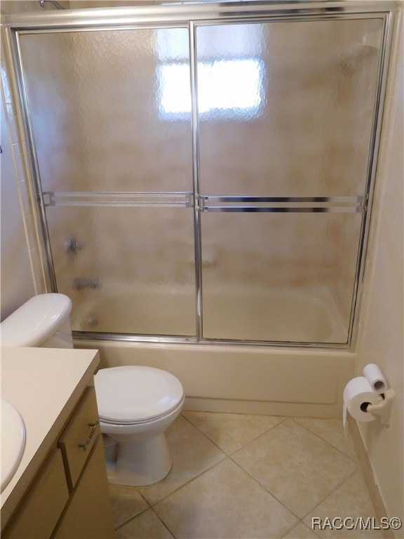 full bathroom featuring vanity, combined bath / shower with glass door, tile patterned floors, and toilet