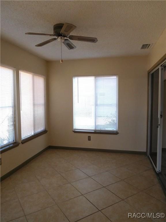 tiled spare room with ceiling fan and a textured ceiling