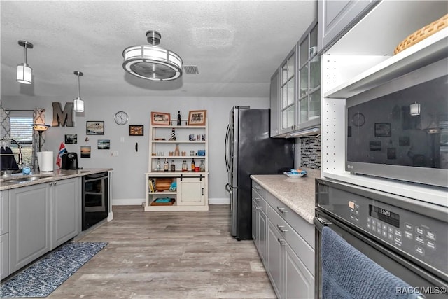 9844 SW 198th Cir, Dunnellon, FL 34432 - kitchen with a sink, a textured ceiling, gray cabinets, black oven, and wine cooler