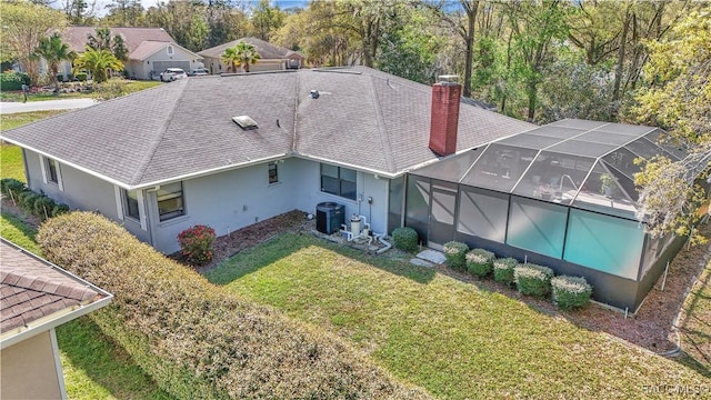 9844 SW 198th Cir, Dunnellon, FL 34432 - back of house with glass enclosure, central air condition unit, a chimney, a lawn, and stucco siding