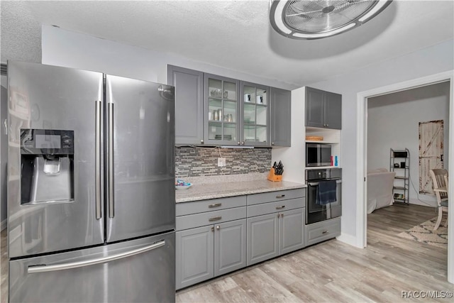 9844 SW 198th Cir, Dunnellon, FL 34432 - kitchen with backsplash, light wood-style flooring, appliances with stainless steel finishes, and gray cabinetry