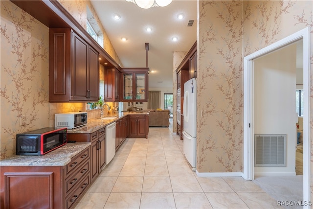 kitchen with vaulted ceiling, sink, light tile patterned floors, light stone countertops, and white appliances