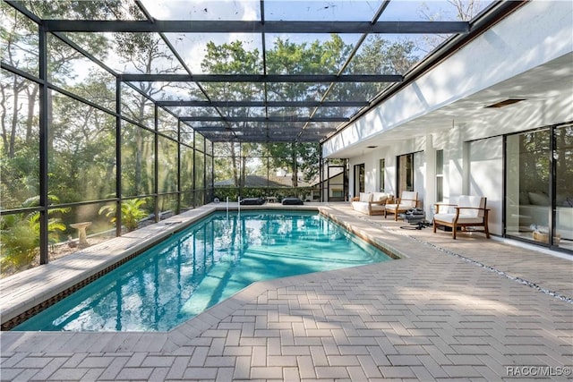 pool with a patio, outdoor lounge area, and glass enclosure