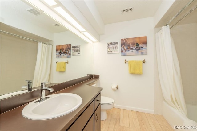 full bathroom featuring vanity, hardwood / wood-style floors, shower / tub combo, and toilet