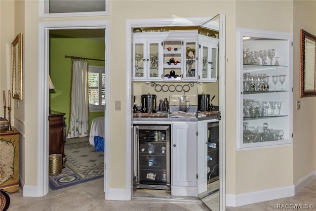 bar featuring wine cooler, white cabinets, and light tile patterned flooring