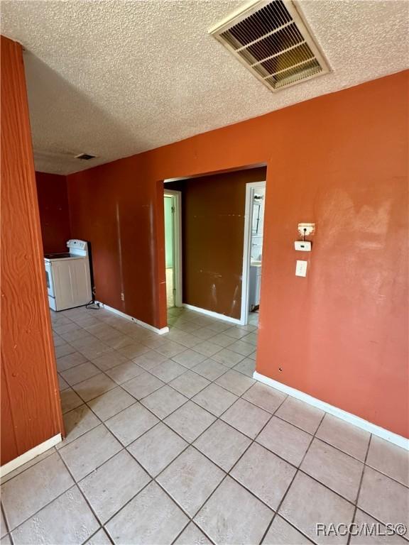 tiled spare room featuring a textured ceiling