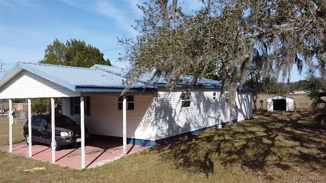 rear view of property featuring a carport, a storage shed, and a yard