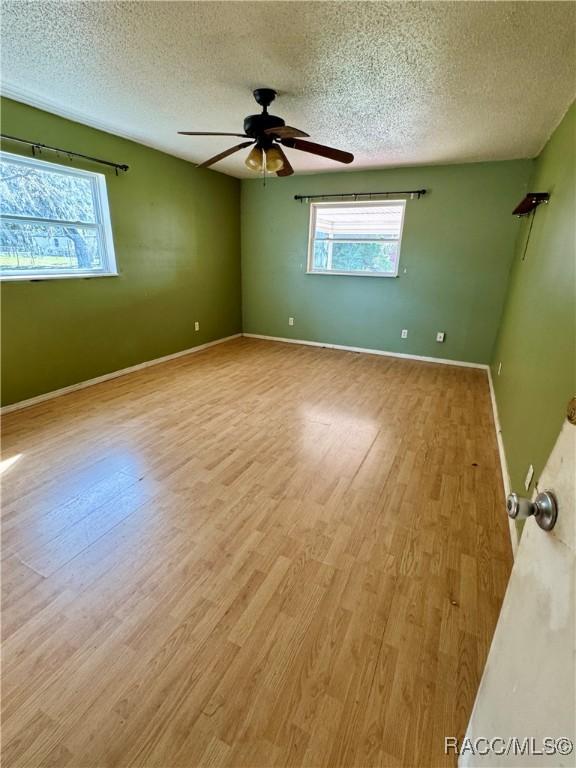 unfurnished room featuring light wood-type flooring, a textured ceiling, and ceiling fan