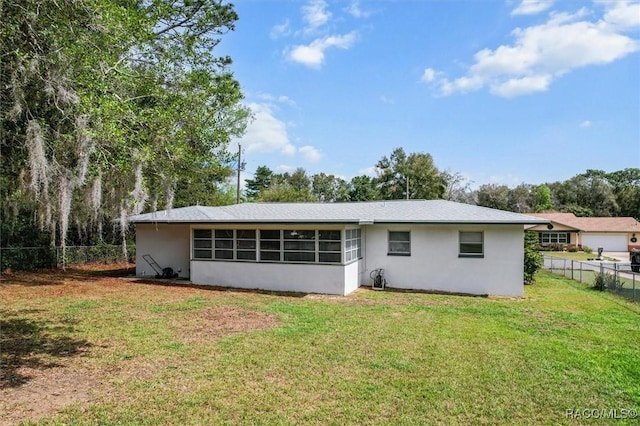 back of property featuring a sunroom, stucco siding, a yard, and fence