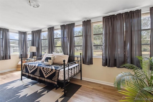 bedroom featuring light wood finished floors, multiple windows, and baseboards