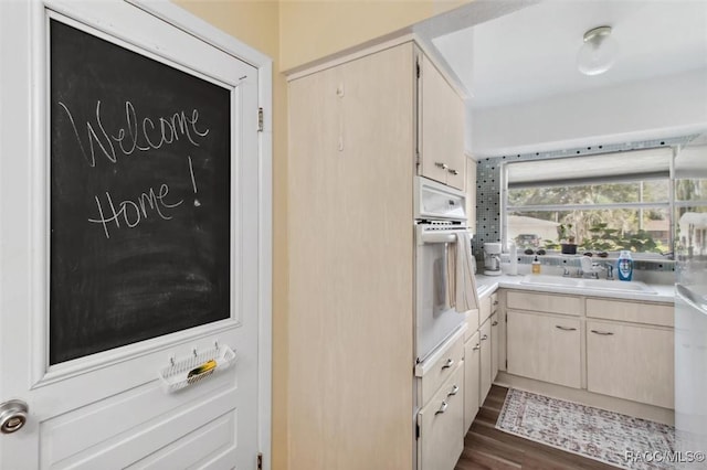 kitchen featuring dark wood finished floors, light countertops, a sink, and white oven